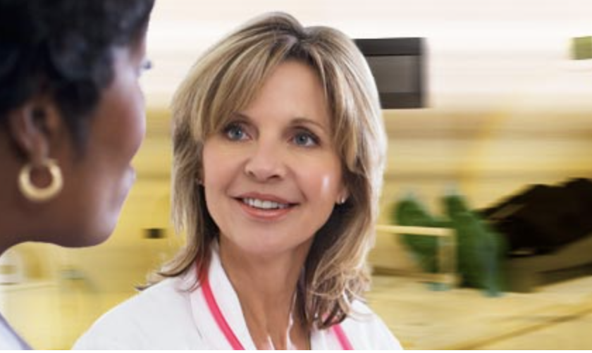 White female doctor with lab coat blurry MRI machine in background