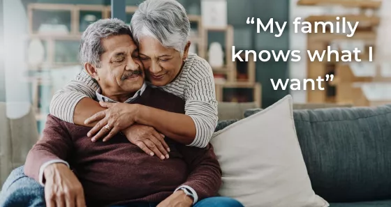 Photo of an older indian couple - male and female, female standing with arms around sitting male with quote "My family knows what I want" overlayed